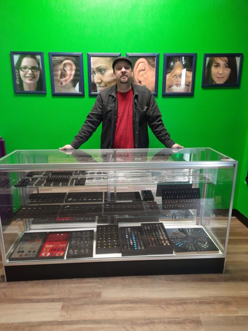 Studio owner behind display case with gallery of piercing photos